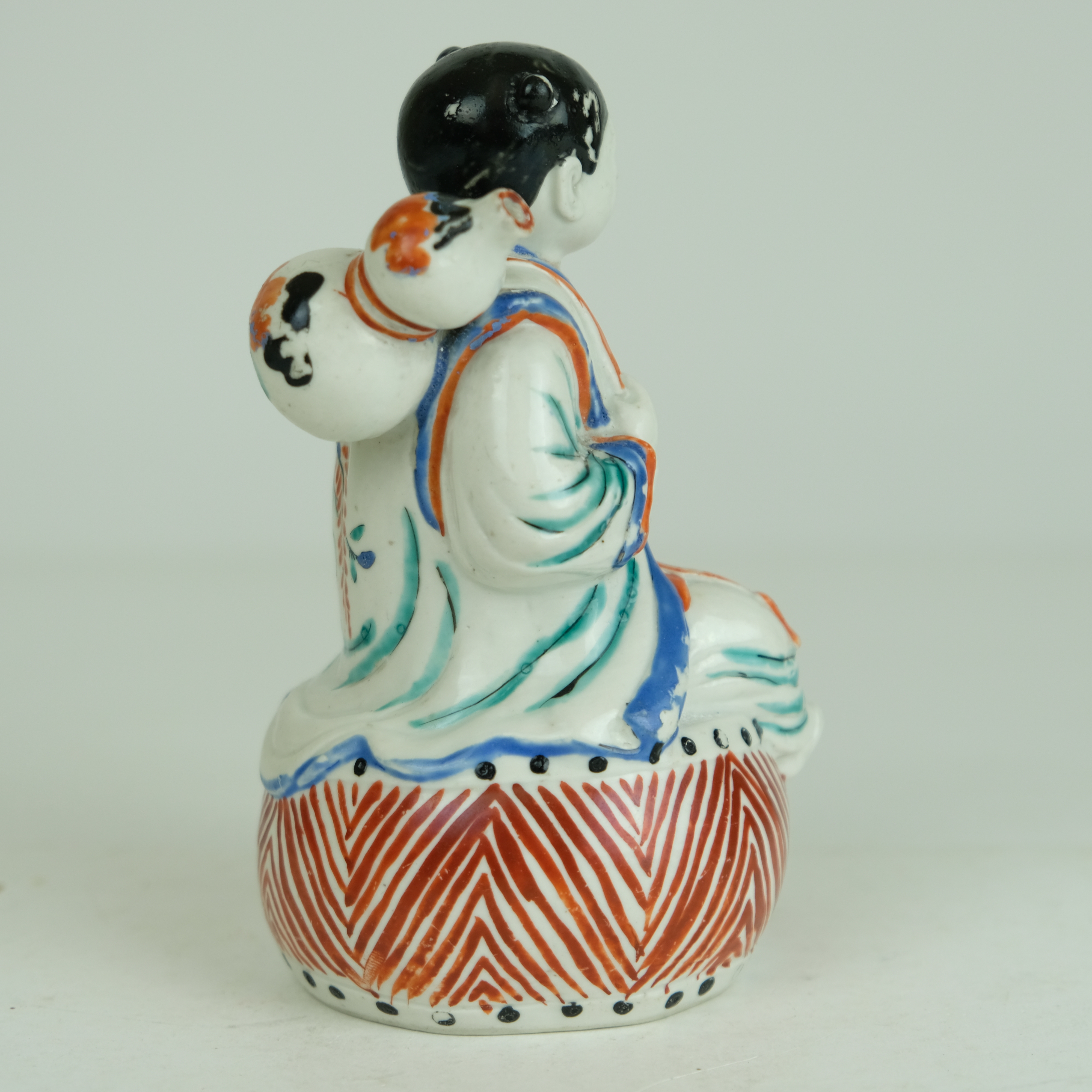 Japanese Kakiemon figure of a boy sitting on a drum. - Detail